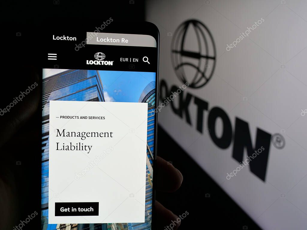 Stuttgart, Germany - 06-05-2025: Person holding cellphone with webpage of financial services company Lockton Companies on screen in front of logo. Focus on center of phone display.