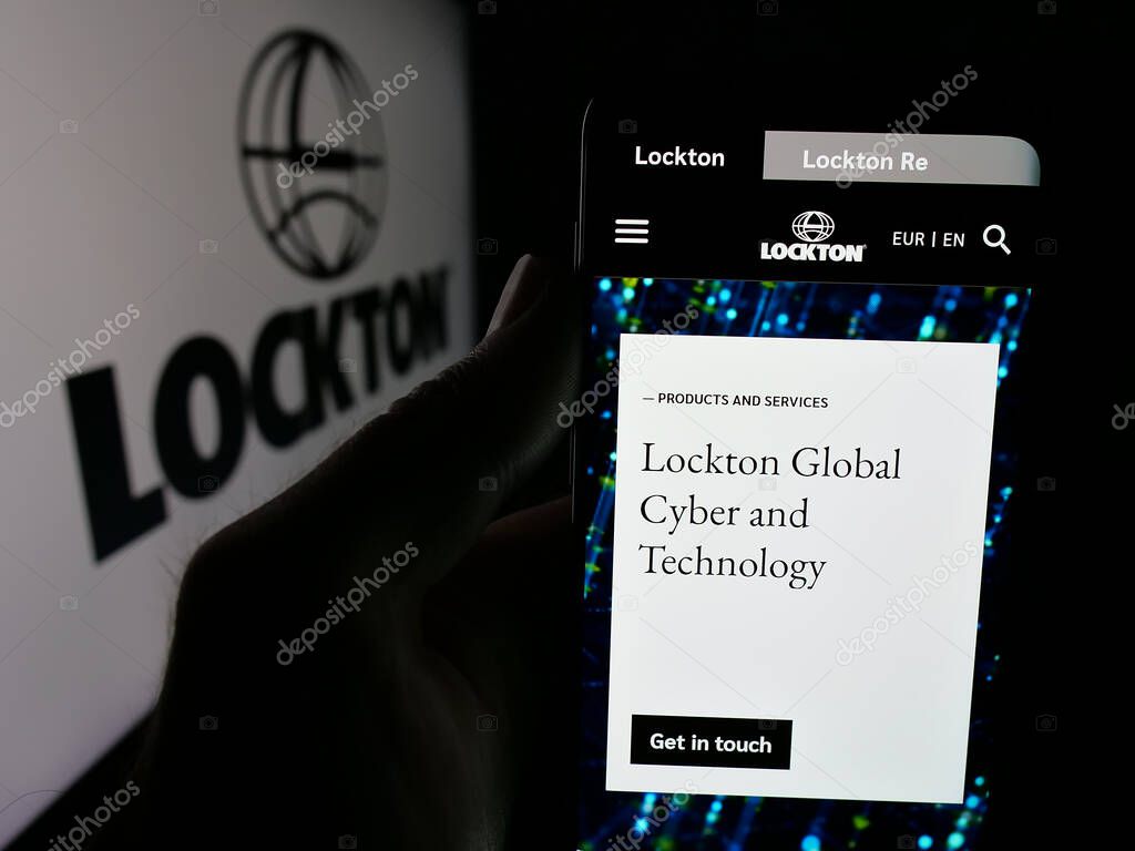 Stuttgart, Germany - 06-05-2025: Person holding smartphone with web page of financial services company Lockton Companies on screen in front of logo. Focus on center of phone display.
