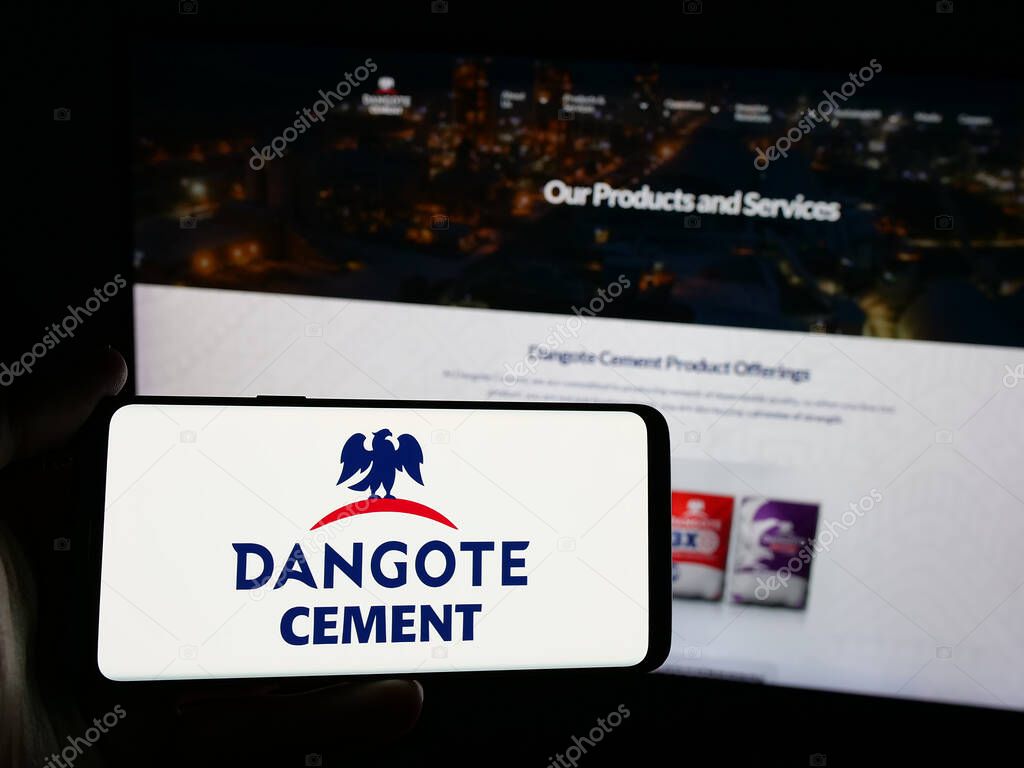 Stuttgart, Germany - 06-05-2025: Person holding smartphone with logo of Nigerian materials company Dangote Cement plc on screen in front of website. Focus on phone display.