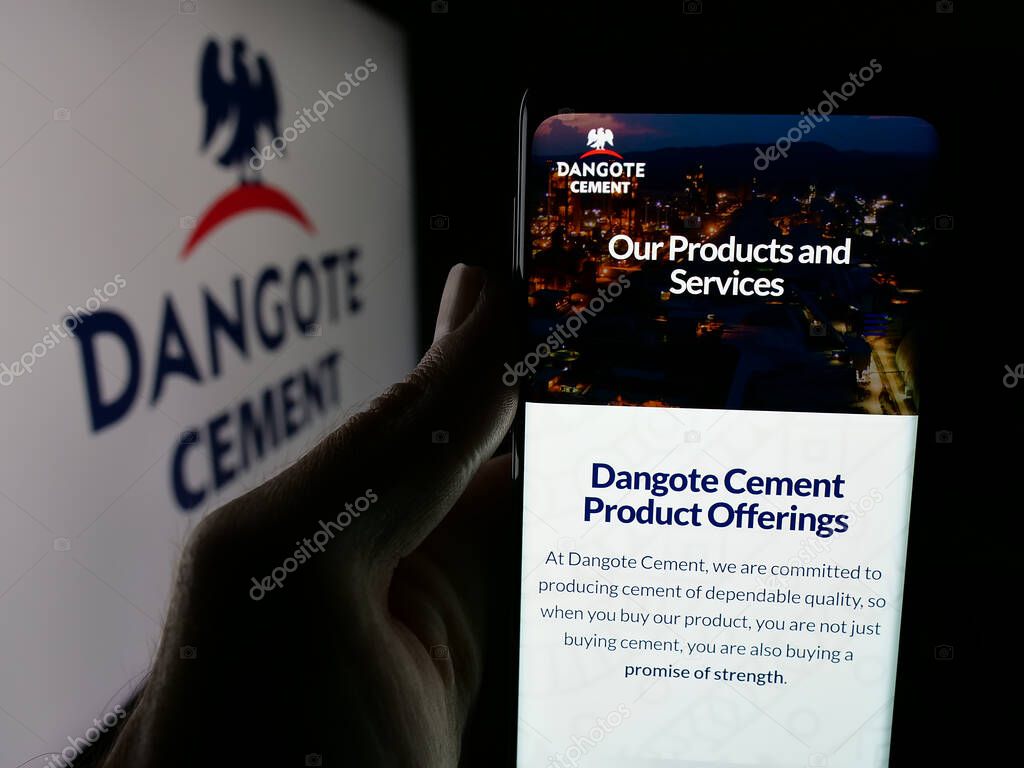 Stuttgart, Germany - 06-05-2025: Person holding smartphone with web page of Nigerian materials company Dangote Cement plc on screen in front of logo. Focus on center of phone display.