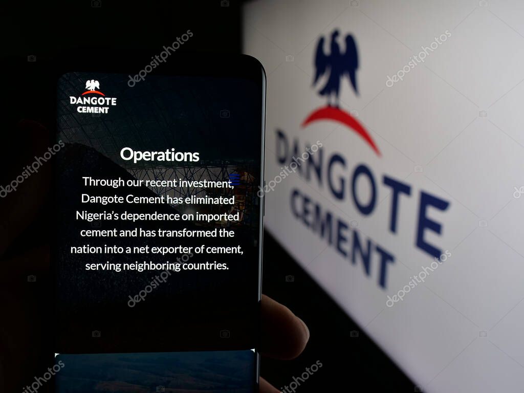 Stuttgart, Germany - 06-05-2025: Person holding cellphone with webpage of Nigerian materials company Dangote Cement plc on screen in front of logo. Focus on center of phone display.