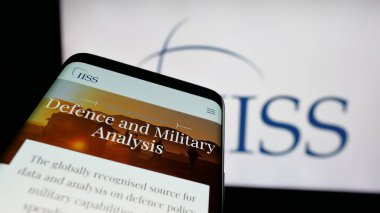 Stuttgart, Almanya - 06-06-2025: İngiliz Stratejik Çalışmalar Enstitüsü 'nün web sitesi logonun önünde ekranda görünen cep telefonu. Telefon ekranının sol üst kısmına odaklan.