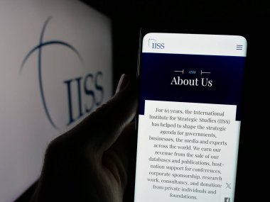 Stuttgart, Almanya - 06-06-2025: İngiliz Stratejik Çalışmalar Enstitüsü 'nün web sayfası olan akıllı telefonu logo önünde ekranda tutan kişi. Telefon ekranının merkezine odaklan.