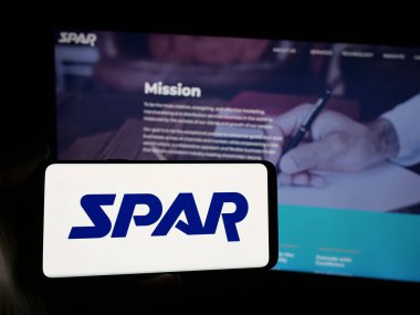 Stuttgart, Almanya - 06-06-2025: Web sitesinin önünde ABD 'li perakende teknoloji şirketi Spar Inc.' in logosunun bulunduğu akıllı telefonu elinde tutan kişi. Telefon ekranına odaklan.