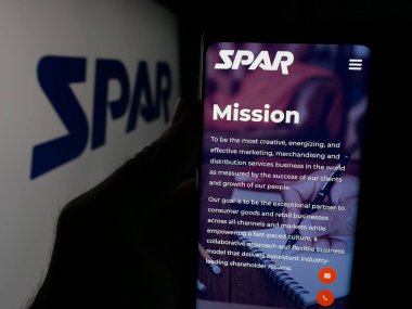 Stuttgart, Almanya - 06-06-2025: ABD 'li perakende teknoloji şirketi Spar Inc.' in web sayfası ile akıllı telefon sahibi kişi logonun önünde ekranda. Telefon ekranının merkezine odaklan.