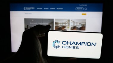Stuttgart, Almanya - 06-06-2025: Web sayfasının önünde ekranda ABD 'li ev yapımı şirketi Champion Homes Inc.' in logosunun bulunduğu cep telefonu sahibi kişi. Telefon ekranına odaklan.