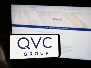 Stuttgart, Almanya - 06-07-2025: Web sitesi önünde ekranda, ABD 'li medya şirketi QVC Group Inc.' in logosunun bulunduğu akıllı telefon sahibi kişi. Telefon ekranına odaklan.