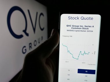 Stuttgart, Almanya - 06-07-2025: ABD 'li medya kuruluşu QVC Group Inc.' in web sayfası ile cep telefonu tutan kişi logo önünde ekranda. Telefon ekranının merkezine odaklan.