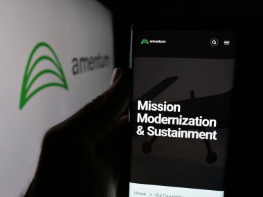 Stuttgart, Almanya - 06-07-2025: ABD 'li müteahhit şirketi Amentum Holding Inc.' nin web sayfası ile akıllı telefon sahibi kişi logo önünde ekranda. Telefon ekranının merkezine odaklan.