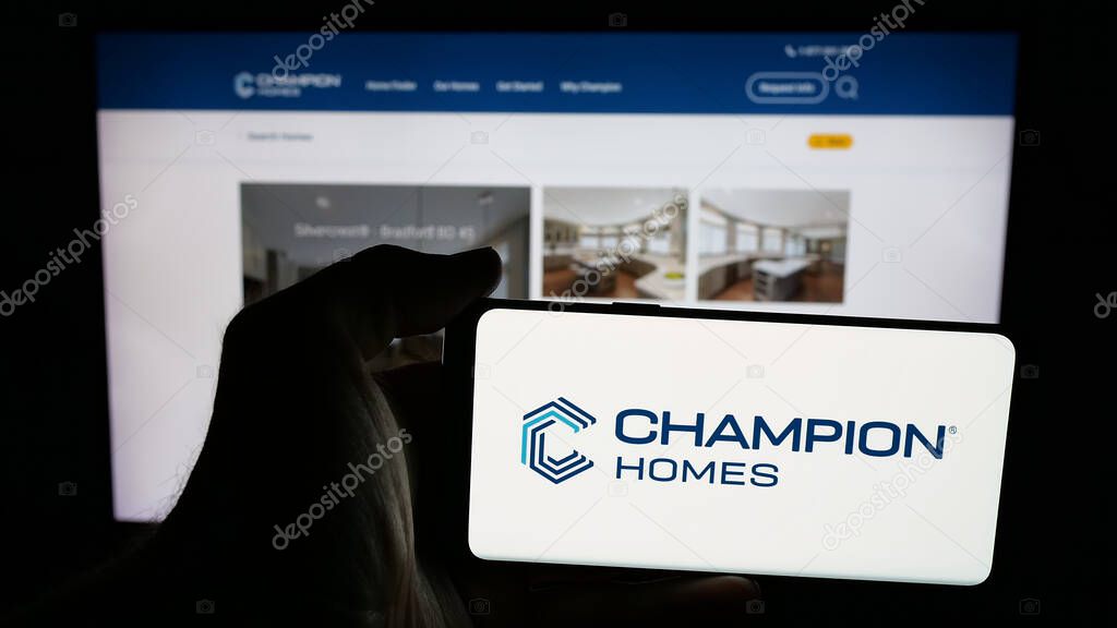 Stuttgart, Germany - 06-06-2025: Person holding mobile phone with logo of US homebuilding company Champion Homes Inc. on screen in front of web page. Focus on phone display.