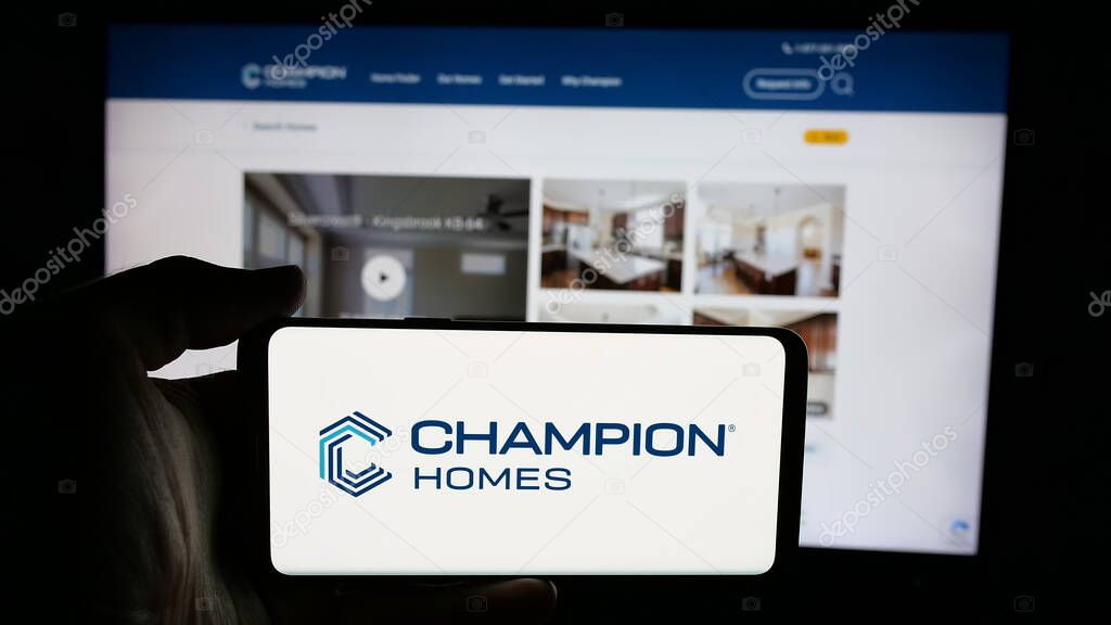 Stuttgart, Germany - 06-06-2025: Person holding cellphone with logo of US homebuilding company Champion Homes Inc. on screen in front of webpage. Focus on phone display.