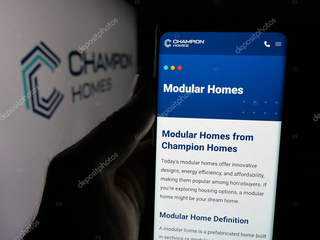 Stuttgart, Germany - 06-06-2025: Person holding smartphone with web page of US homebuilding company Champion Homes Inc. on screen in front of logo. Focus on center of phone display.