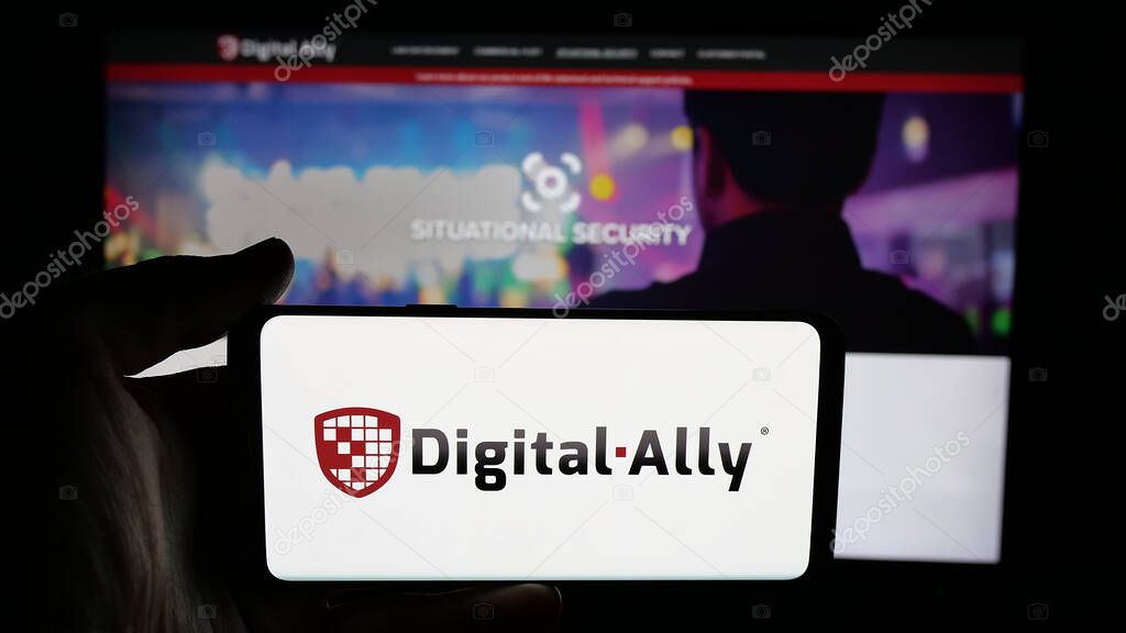 Stuttgart, Germany - 06-07-2025: Person holding cellphone with logo of US video solutions company Digital Ally Inc. on screen in front of webpage. Focus on phone display.