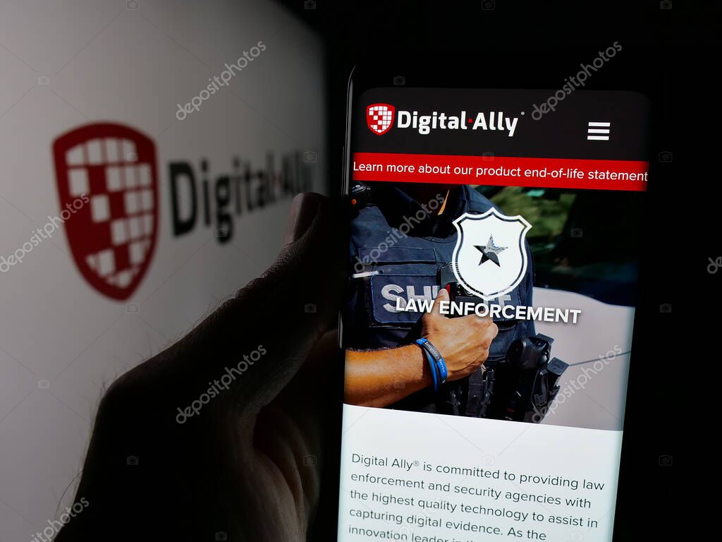 Stuttgart, Germany - 06-07-2025: Person holding cellphone with webpage of US video solutions company Digital Ally Inc. on screen in front of logo. Focus on center of phone display.