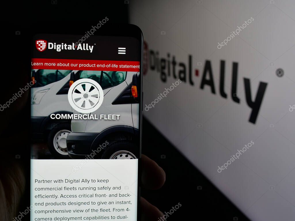 Stuttgart, Germany - 06-07-2025: Person holding smartphone with web page of US video solutions company Digital Ally Inc. on screen in front of logo. Focus on center of phone display.