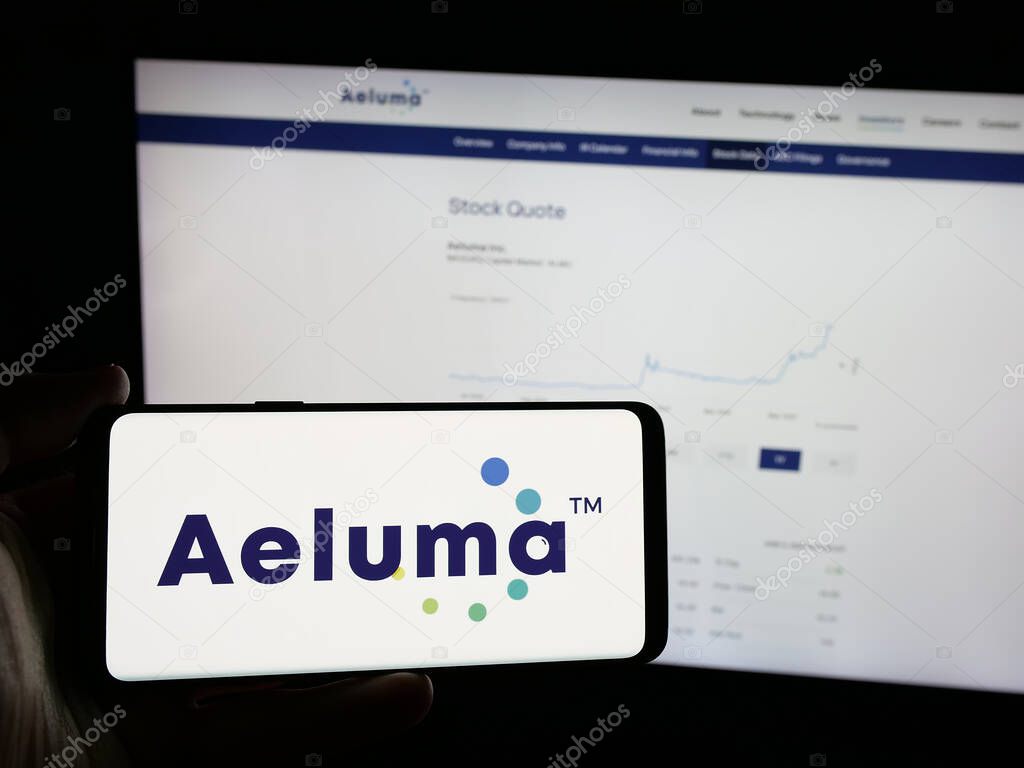 Stuttgart, Germany - 06-07-2025: Person holding smartphone with logo of US semiconductor company Aeluma Inc. on screen in front of website. Focus on phone display.