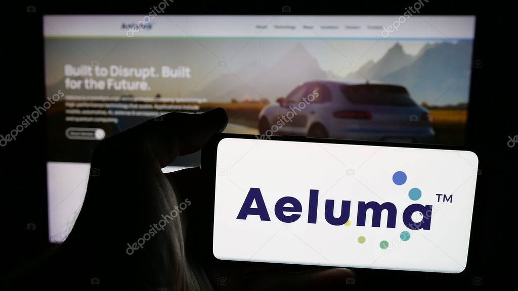 Stuttgart, Germany - 06-07-2025: Person holding mobile phone with logo of US semiconductor company Aeluma Inc. on screen in front of web page. Focus on phone display.