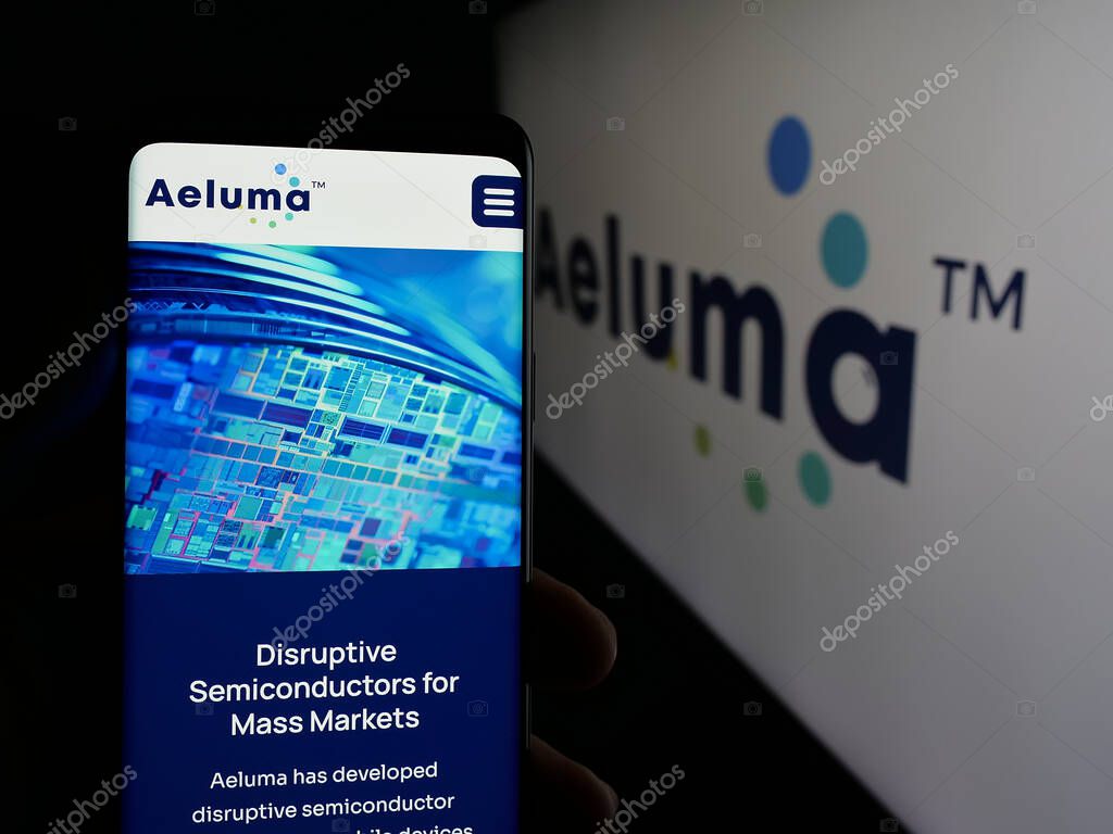 Stuttgart, Germany - 06-07-2025: Person holding cellphone with webpage of US semiconductor company Aeluma Inc. on screen in front of logo. Focus on center of phone display.