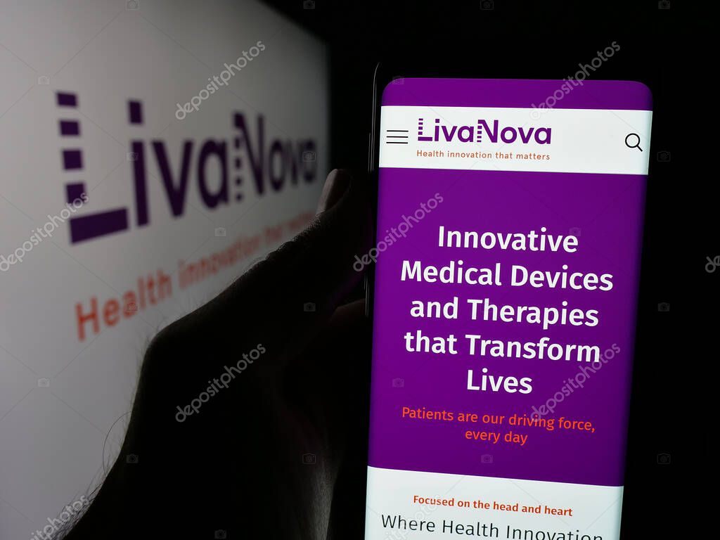 Stuttgart, Germany - 06-07-2025: Person holding cellphone with webpage of medical device company LivaNova plc on screen in front of logo. Focus on center of phone display.
