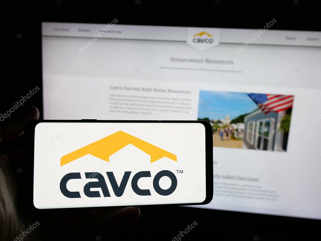 Stuttgart, Germany - 06-07-2025: Person holding smartphone with logo of US homebuilding company Cavco Industries Inc. on screen in front of website. Focus on phone display.