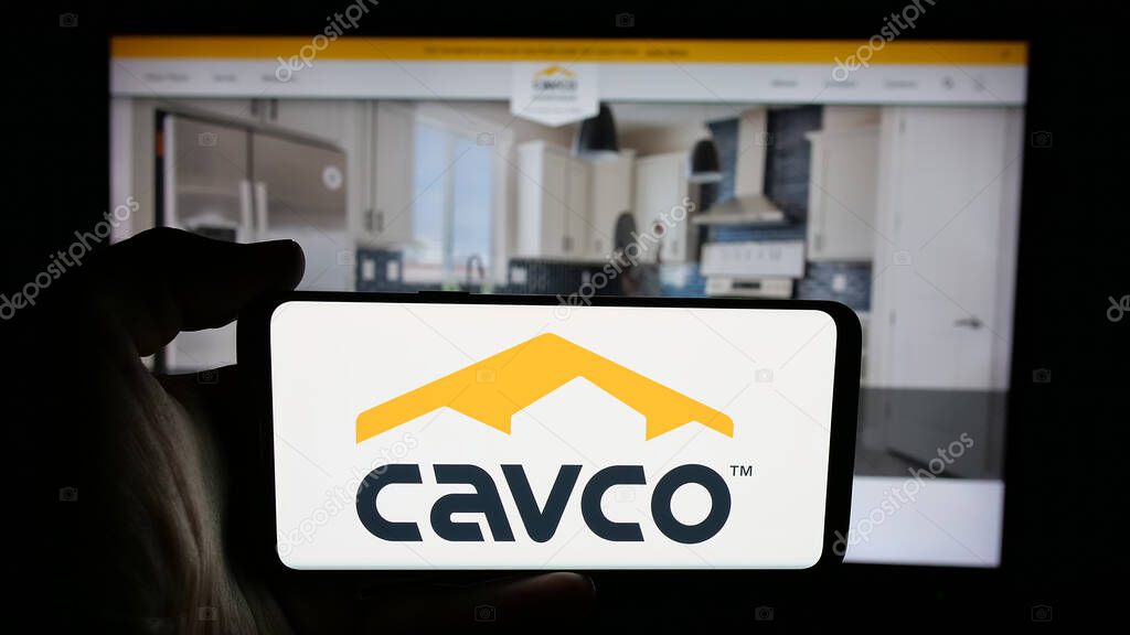 Stuttgart, Germany - 06-07-2025: Person holding cellphone with logo of US homebuilding company Cavco Industries Inc. on screen in front of webpage. Focus on phone display.