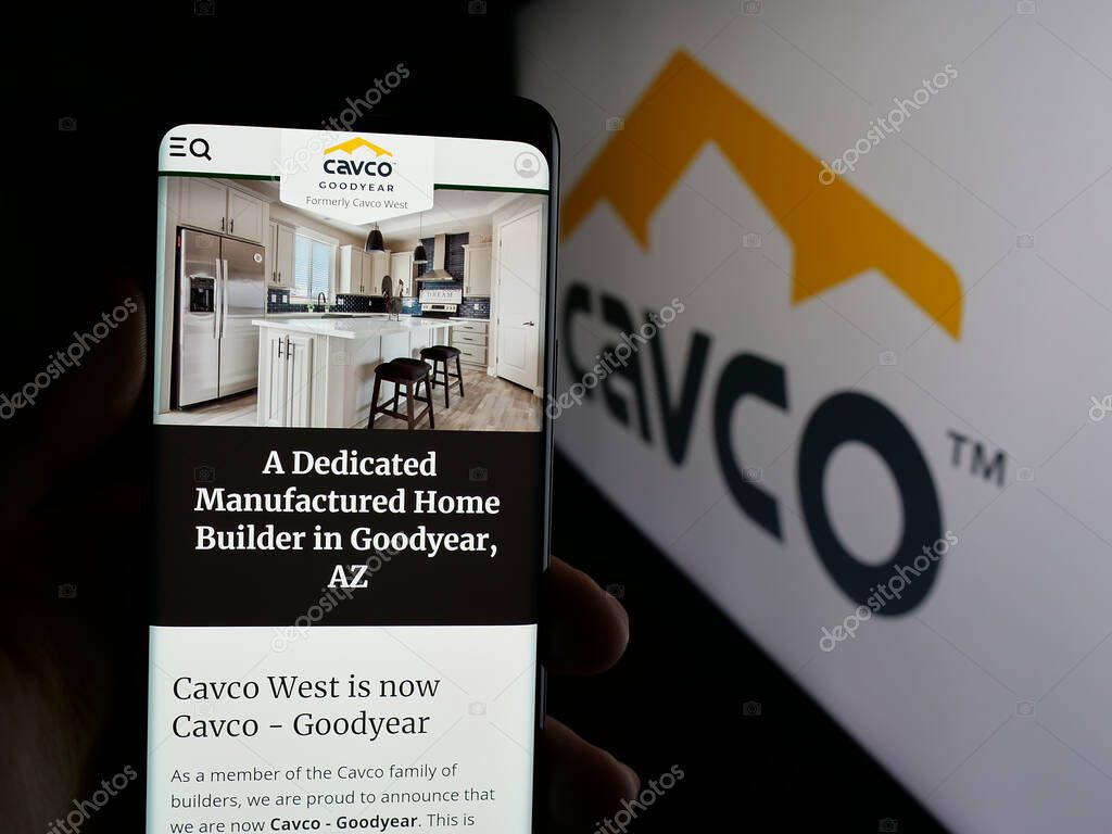 Stuttgart, Germany - 06-07-2025: Person holding cellphone with webpage of US homebuilding company Cavco Industries Inc. on screen in front of logo. Focus on center of phone display.