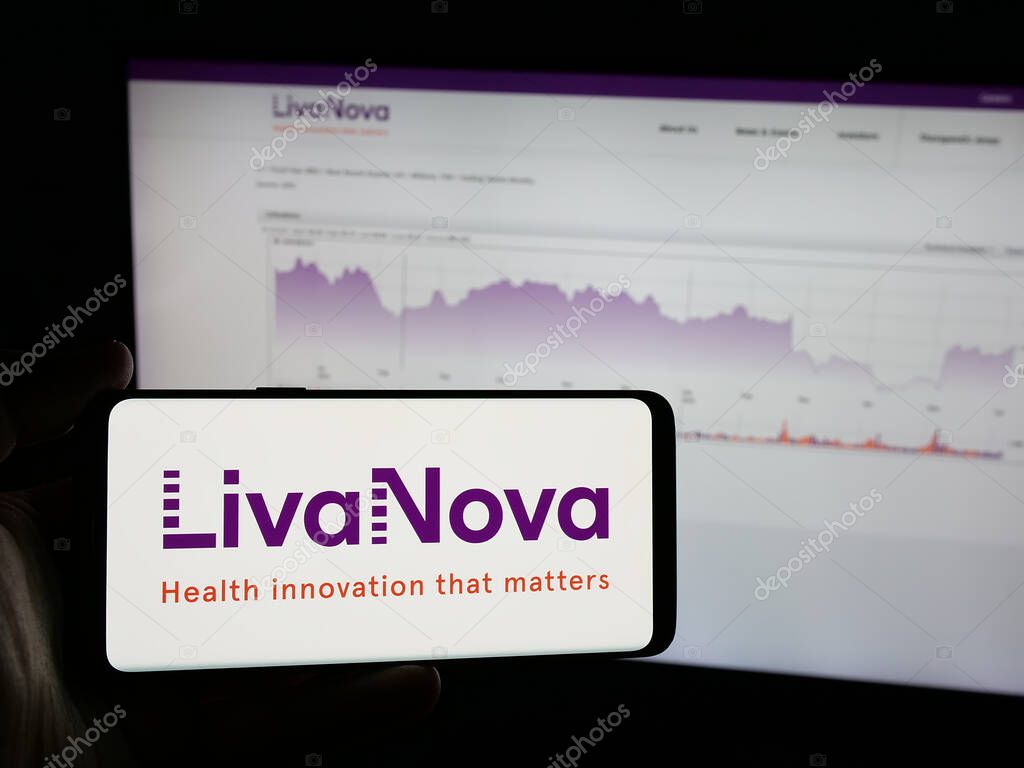 Stuttgart, Germany - 06-07-2025: Person holding smartphone with logo of medical device company LivaNova plc on screen in front of website. Focus on phone display.