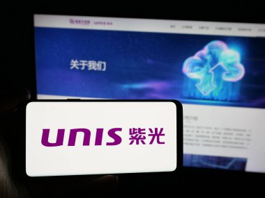 Stuttgart, Almanya - 06-08-2025: Web sitesi önünde ekranda Unisplendour Corporation Limited (UNIS) logosu olan akıllı telefon sahibi kişi. Telefon ekranına odaklan.