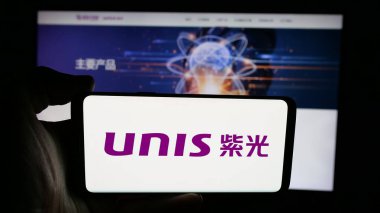 Stuttgart, Almanya - 06-08-2025: Web sayfası önünde Unisplendour Corporation Limited (UNIS) logosu olan cep telefonu sahibi kişi. Telefon ekranına odaklan.