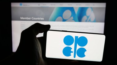 Stuttgart, Almanya - 06-08-2025: İnternet sayfasının önünde ekranda OPEC adlı petrol ihracat organizasyonunun logosunu taşıyan cep telefonu sahibi. Telefon ekranına odaklan.