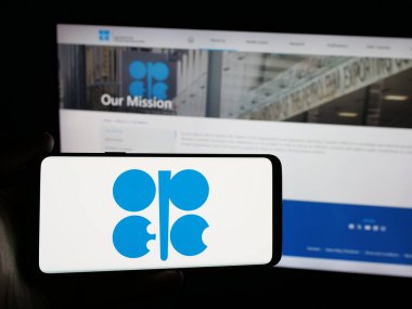 Stuttgart, Almanya - 06-08-2025: İnternet sitesi önünde ekranda OPEC adlı petrol ihracat organizasyonunun logosunu taşıyan kişi. Telefon ekranına odaklan.