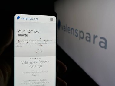 Stuttgart, Almanya - 06-08-2025: Türk şirketi ValensPara Odeme Kurulusu 'nun internet sayfası ile akıllı telefon sahibi kişi logo önünde ekranda. Telefon ekranının merkezine odaklan.