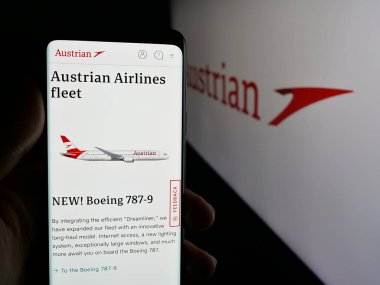 Stuttgart, Almanya - 06-09-2025: Havayolu şirketi AG 'nin (AUA) web sayfası logonun önünde bulunan kişi. Telefon ekranının merkezine odaklan.