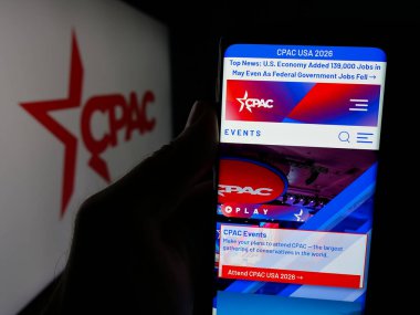 Stuttgart, Almanya - 06-09-2025: Siyasi eylem konferans etkinliğinin web sayfası ile akıllı telefonu logo önünde ekranda tutan kişi. Telefon ekranının merkezine odaklan.
