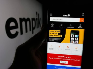 Stuttgart, Almanya - 06-09-2025: Polonyalı perakende şirketi Empik S.A. 'nın web sayfası olan akıllı telefon sahibi kişi logonun önünde ekranda. Telefon ekranının merkezine odaklan.