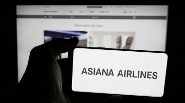 Stuttgart, Almanya - 06-09-2025: Koreli havayolu şirketi Asiana Airlines 'ın logosunun bulunduğu cep telefonu sahibi kişi web sayfasının önünde ekranda. Telefon ekranına odaklan.