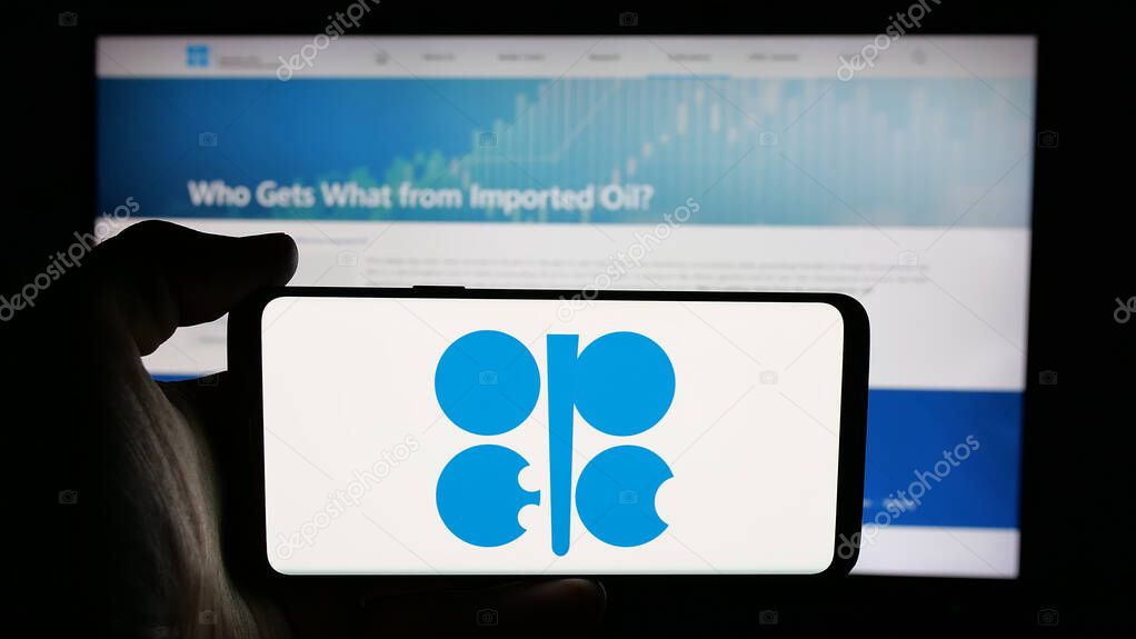 Stuttgart, Germany - 06-08-2025: Person holding cellphone with logo of petroleum exporting organization OPEC on screen in front of webpage. Focus on phone display.