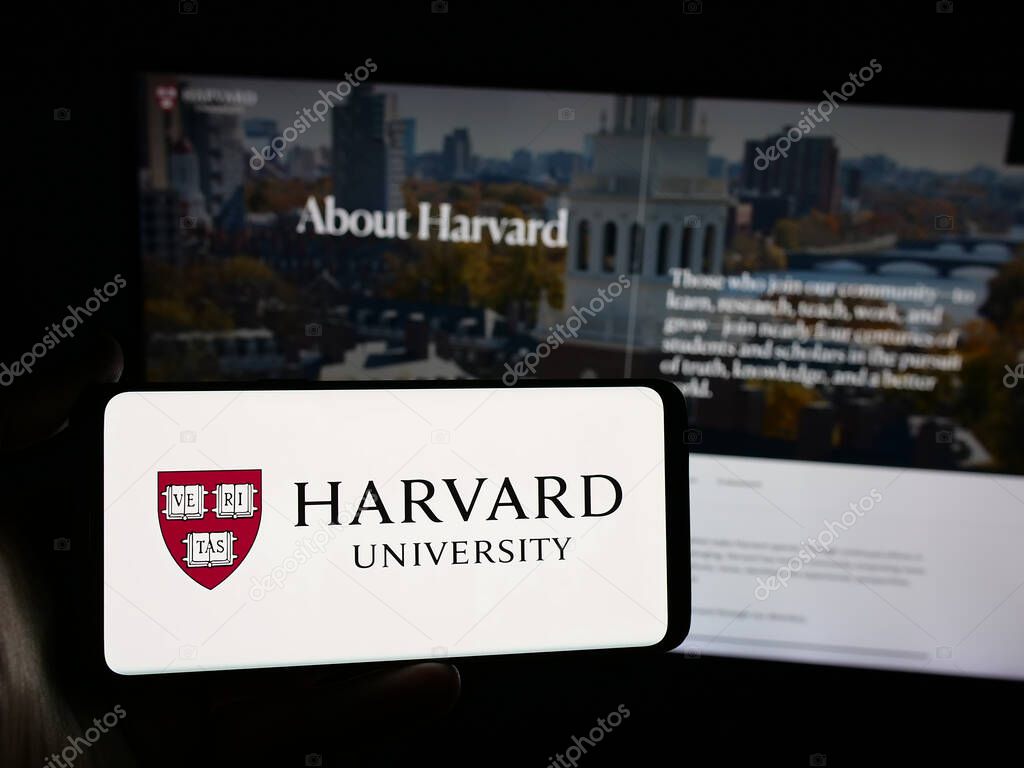 Stuttgart, Germany - 06-09-2025: Person holding smartphone with logo of US research institution Harvard University on screen in front of website. Focus on phone display.