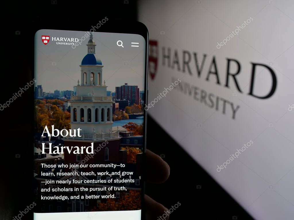 Stuttgart, Germany - 06-09-2025: Person holding smartphone with web page of US research institution Harvard University on screen in front of logo. Focus on center of phone display.