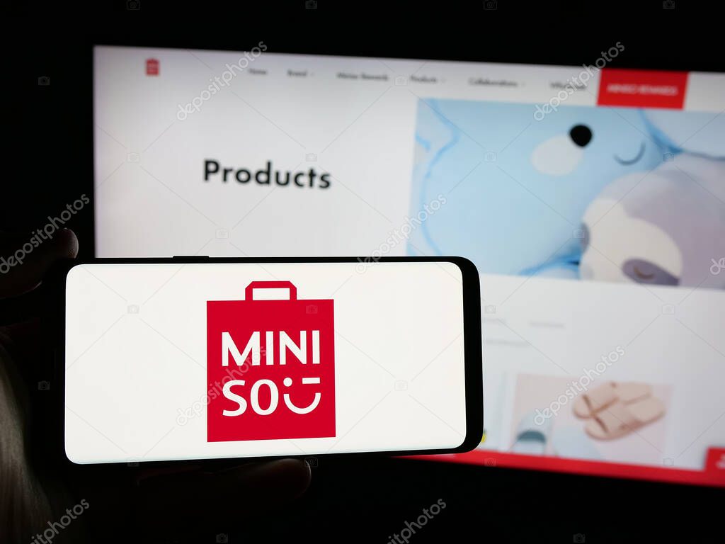 Stuttgart, Germany - 06-09-2025: Person holding smartphone with logo of retail company MINISO Group Holding Limited on screen in front of website. Focus on phone display.