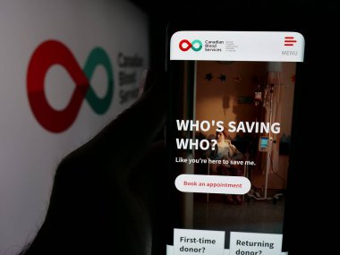 Stuttgart, Almanya - 06-09-2025: Kanada Kan Hizmetleri adlı sağlık kuruluşunun internet sayfası logonun önünde duran kişi. Telefon ekranının merkezine odaklan.