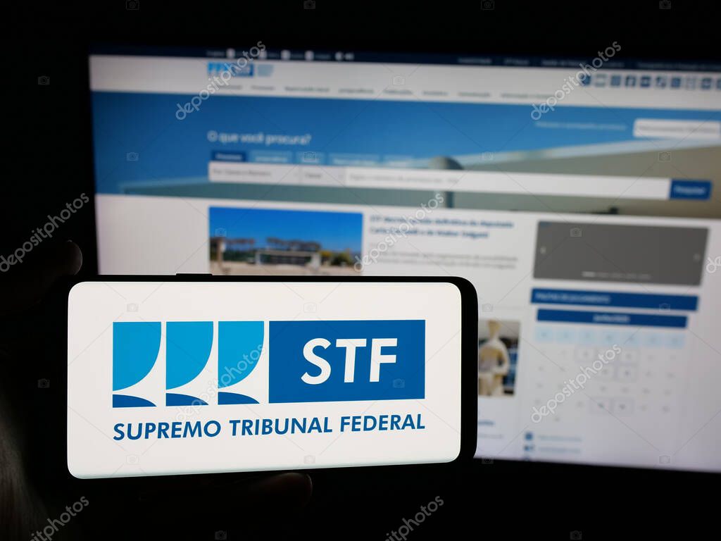 Stuttgart, Germany - 06-09-2025: Person holding smartphone with logo of Brazil court Supremo Tribunal Federal (STF) on screen in front of website. Focus on phone display.
