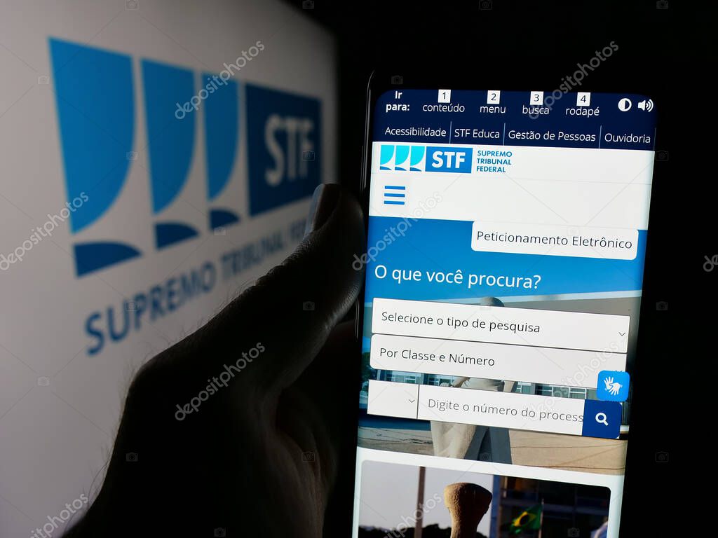 Stuttgart, Germany - 06-09-2025: Person holding smartphone with web page of Brazil court Supremo Tribunal Federal (STF) on screen in front of logo. Focus on center of phone display.