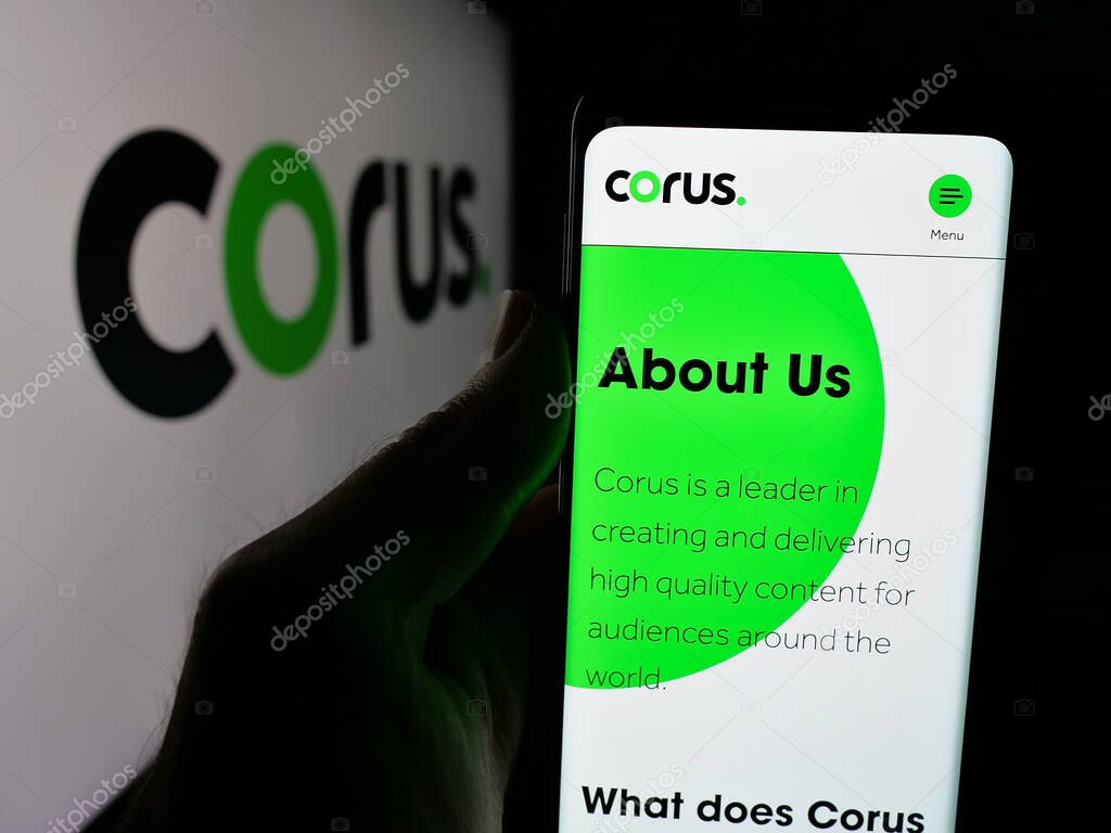Stuttgart, Germany - 06-09-2025: Person holding cellphone with webpage of media company Corus Entertainment Inc. on screen in front of logo. Focus on center of phone display.