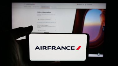 Stuttgart, Almanya - 06-11-2025: Havayolu şirketi Societe Air France S.A. 'nın logosuyla cep telefonu tutan kişi web sayfasının önünde ekranda. Telefon ekranına odaklan.