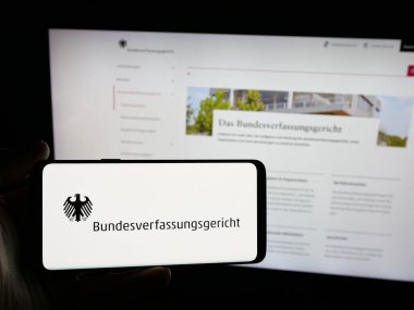 Stuttgart, Almanya - 06-11-2025: İnternet sitesi önünde Bundesverfassungsgert (BVerfG) mahkemesinin logosuna sahip akıllı telefon sahibi kişi. Telefon ekranına odaklan.