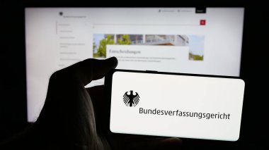 Stuttgart, Almanya - 06-11-2025: İnternet sayfasının önünde Bundesverfassungsgericht (BVerfG) mahkemesinin logosu olan cep telefonu sahibi kişi. Telefon ekranına odaklan.