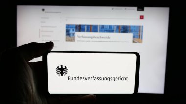 Stuttgart, Almanya - 06-11-2025: İnternet sayfası önünde Bundesverfassungsgericht (BVerfG) mahkemesinin logosu olan cep telefonu sahibi. Telefon ekranına odaklan.