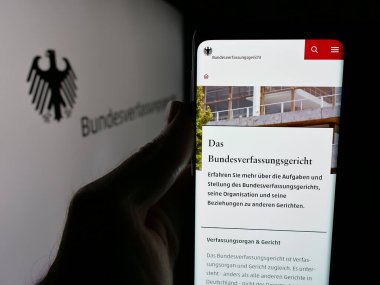 Stuttgart, Almanya - 06-11-2025: Mahkeme Bundesverfassungsgericht (BVerfG) web sayfası logonun önünde cep telefonu tutan kişi. Telefon ekranının merkezine odaklan.