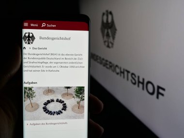 Stuttgart, Almanya - 06-11-2025: Alman federal mahkemesi Bundesgerichtshof 'un (BGH) web sayfası logonun önünde cep telefonu tutan kişi. Telefon ekranının merkezine odaklan.